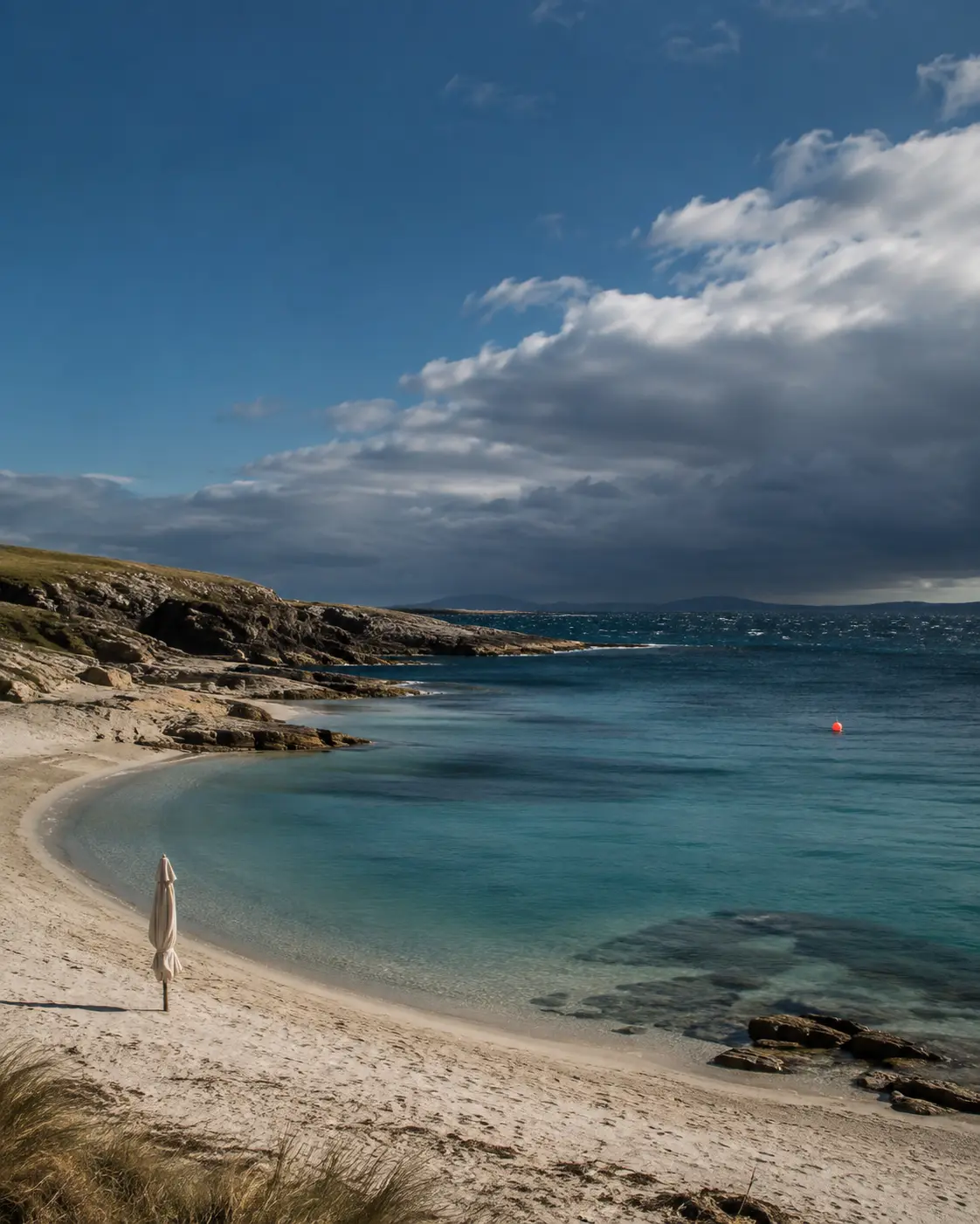 Calm shoulder-season bay beneath an approaching offshore weather line