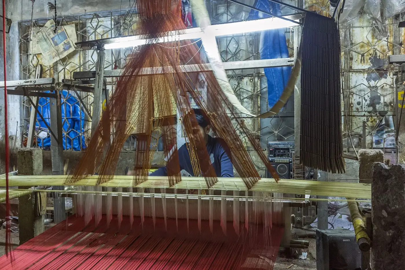 A craftsperson working at a handloom in a weaving workshop