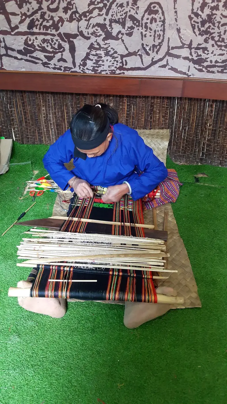 A Li craftsperson working with a traditional body-tensioned loom in Hainan, China