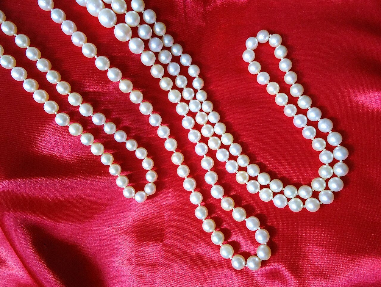 Japanese Akoya cultured pearl strands arranged on red fabric