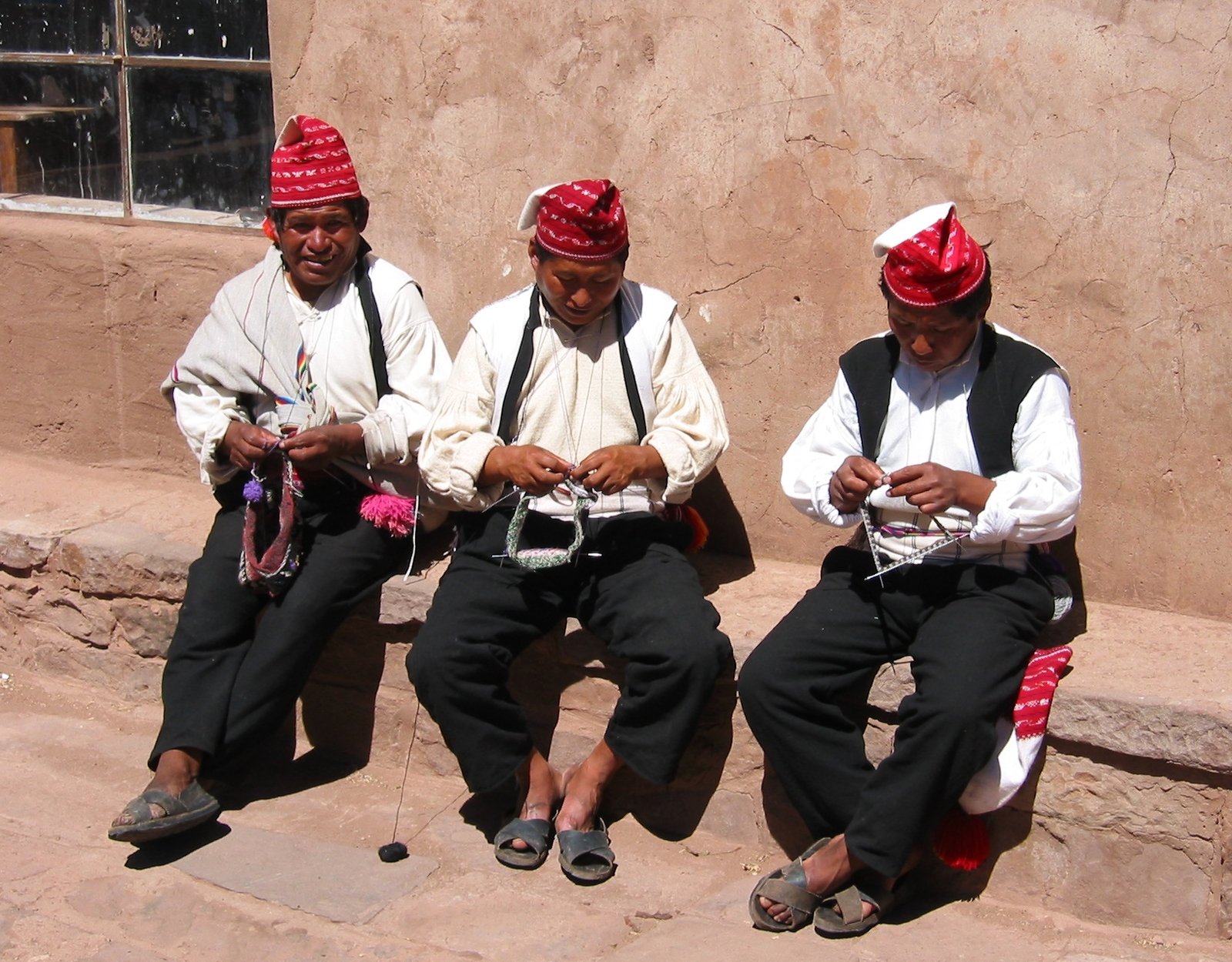 Three men knitting traditional textiles on Taquile Island in Lake Titicaca, Peru